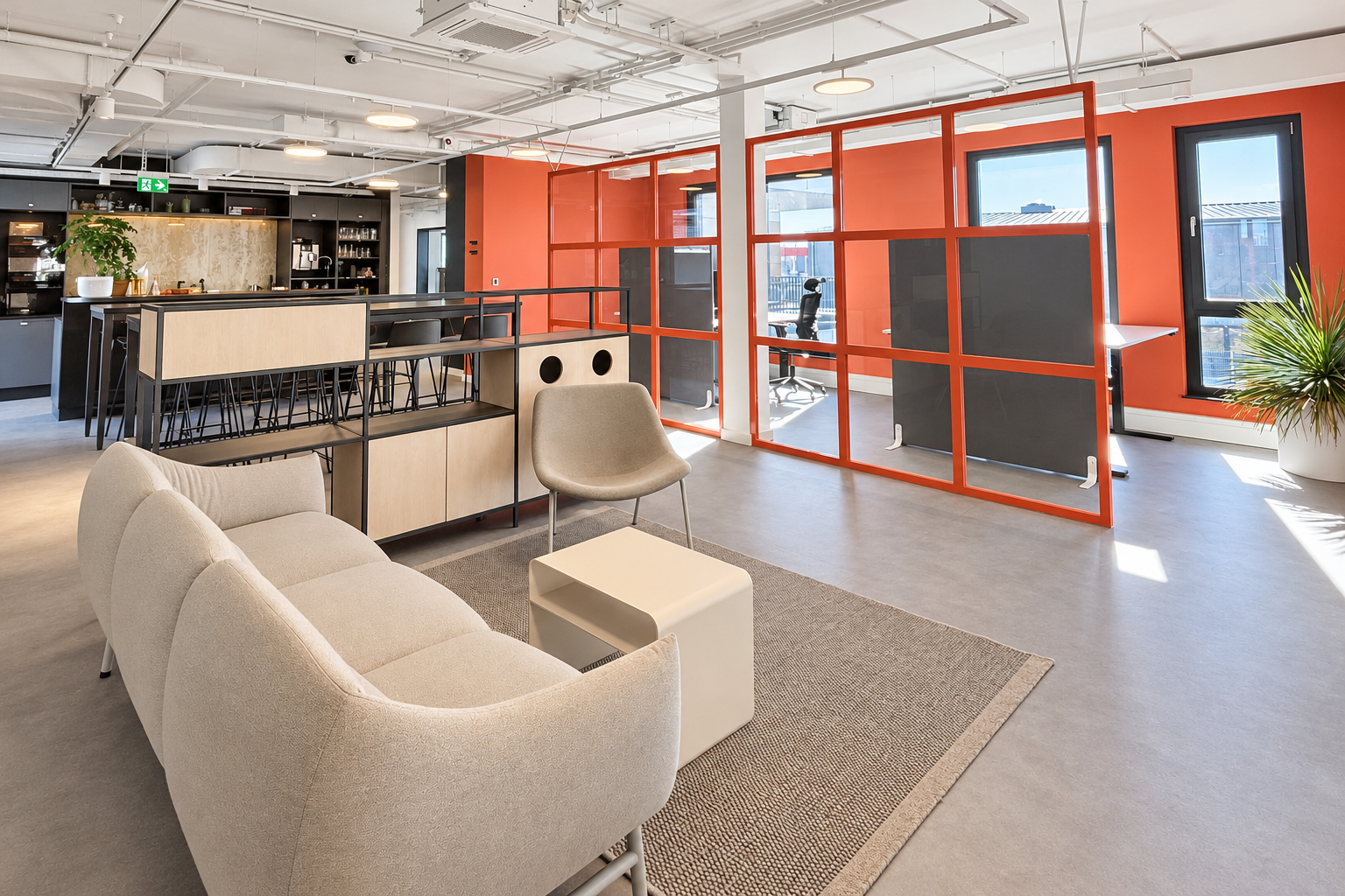 Coworking-Lounge im innospace Haßloch mit Sofa, Küche und coralfarbenem Raumteiler